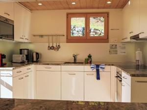 una cucina con mobili bianchi e un fiocco blu sul bancone di Chalet Chalet Pitschun by Interhome a Grindelwald