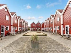 a row of red houses with benches in a courtyard at Holiday Home Alissa - 400m from the sea by Interhome in Fanø