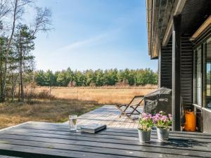 a wooden deck with a table with books and flowers at Holiday Home Shayene - 2-5km from the sea by Interhome in Læsø