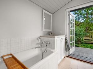 a white bath tub in a bathroom with a window at Holiday Home Teijo - 2-5km from the sea by Interhome in Ebeltoft +13 photos