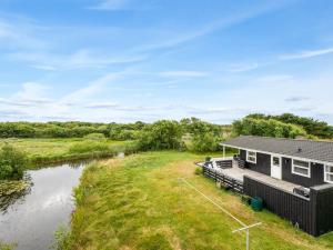 a house with a deck next to a river at Holiday Home Bentine - 400m from the sea by Interhome in Fanø