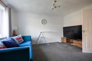 een woonkamer met een blauwe bank en een tv bij Stanhope - Sizewell - Contractor Accommodation in Snape