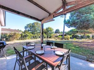 una mesa de madera con sillas en el patio en Holiday Home Les Arbousiers by Interhome, en Vendays-Montalivet