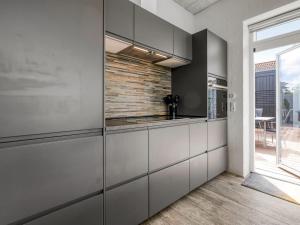 a kitchen with white cabinets and a brick wall at Holiday Home Bondi - 75m from the sea by Interhome in Knebel