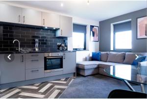 eine Küche und ein Wohnzimmer mit einer Couch und einem Tisch in der Unterkunft The Aurelia Apartments VII - 1 Bed Apartment in Peterborough