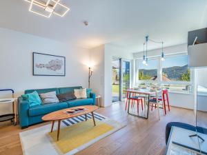 een woonkamer met een blauwe bank en een tafel bij Apartment Top 5 Alpe maritima Seeblick-Bergkulisse by Interhome in Annenheim