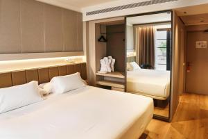 a hotel room with two beds and a mirror at Hotel Bécquer in Seville