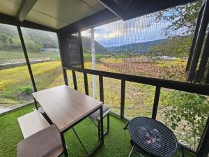 a table and a chair on a balcony with a view at Danyang Kotdle Moolgam Chatki Pension in Danyang