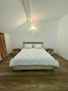 Un dormitorio blanco con una cama y dos mesitas de noche. en Imperial, en Moisei