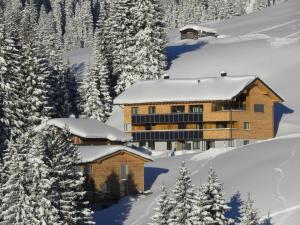 eine Lodge im Schnee mit schneebedeckten Bäumen in der Unterkunft Flora Alpinea in Damüls