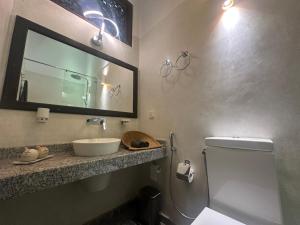 a bathroom with a sink and a mirror and a toilet at Niyagama House in Galle