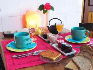 Una mesa con dos tazas azules y pan y bebidas. en Sferenn - Chambre D'hôtes, en Baden