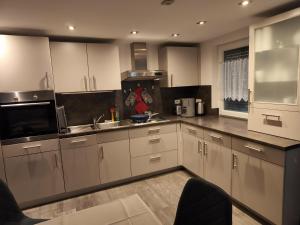 a kitchen with white cabinets and stainless steel appliances at Ferienwohnung zwischen Steigerwald und Frankenhöhe für 2-3 Personen, barrierefrei in Gallmersgarten +3 photos