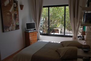a bedroom with a bed and a television and a window at Villa Nara in La Bouilladisse