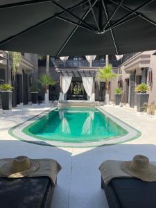 马拉喀什马诺别墅的庭院内的游泳池,配有遮阳伞