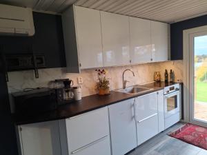 a kitchen with white cabinets and a sink at Tofta in Växjö
