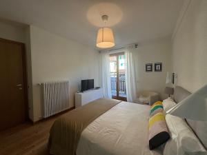 a bedroom with a white bed and a television at Siera Loft 1 - Panorama a 3 Minuti dalle Piste in Ecche