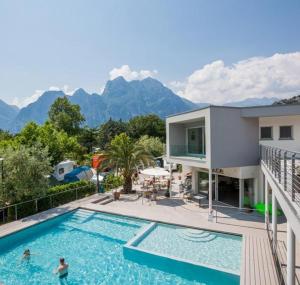 a house with a swimming pool with mountains in the background at Holiday Apartments - Camping Al Porto in Nago-Torbole