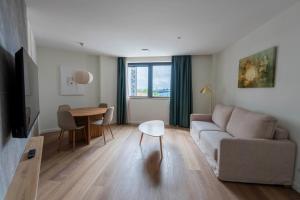 Silken Apartamentos Goya في أوفِييذو: غرفة معيشة بها أريكة وطاولة