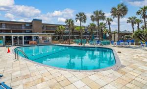 a large swimming pool with blue chairs and palm trees at Island House BeachFront Condo Hotel in Corpus Christi