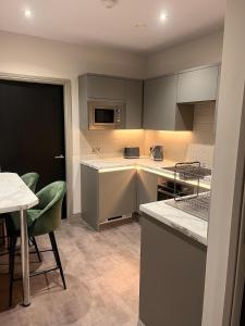 a kitchen with gray cabinets and a table and chairs at The Jesmond Hideaway - Cosy Modern Apartment in Jesmond