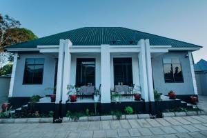 a white house with a green roof and a patio at Royal Homestay in Moshi