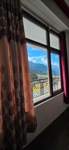 a window with a view of a mountain view at Hotel Thangshing In in Lachung +13 photos