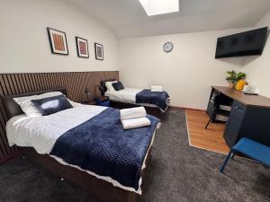 a bedroom with two beds and a desk and a television at Core Citi Lets, Guild Street Rooms in Aberdeen +4 photos
