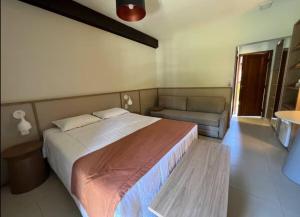 a bedroom with a large bed and a couch at Suíte luxo in Maresias