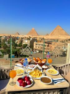 a table with food on it with pyramids in the background at Continental Pyramids Terrace Hotel in Cairo