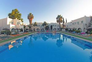 ein großer blauer Swimmingpool mit Palmen und Gebäuden in der Unterkunft Hotel Bağevleri in Gümbet
