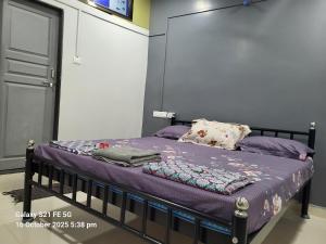 a bed with purple sheets and pillows in a room at Datta Swami Homestay in Malvan