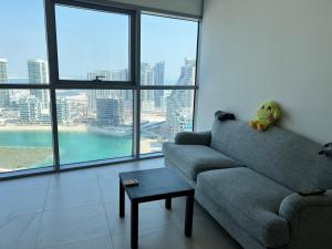 a living room with a couch and large windows at Cozy Room In Abu Dhabi Reem island Near to Galeria Mall in Abu Dhabi