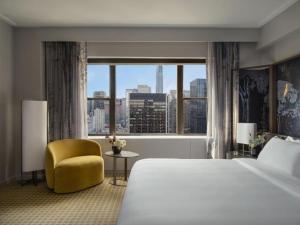 a bedroom with a large bed and a yellow chair and a window at Hotel The Caves in New Delhi