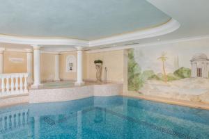 a swimming pool in a building with a painting on the wall at Hotel Evaldo in Arabba