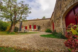 an external view of a stone building with red doors at annexe du Mesnil in Le Tourne
