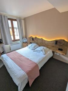 Un dormitorio con una cama grande con cabecero de madera. en Hotel le Chasseur, en Illkirch-Graffenstaden