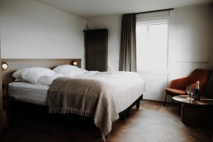 ein Schlafzimmer mit einem Bett und einem Stuhl und einem Fenster in der Unterkunft Bryggjan Boutique Hotel in Akureyri