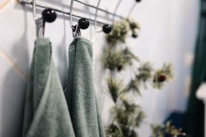 two green towels hanging on a rack with plants at Santa's closest neighbor in Rovaniemi