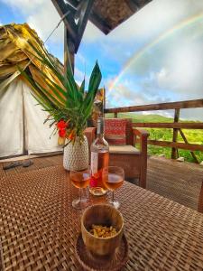 een tafel met twee glazen wijn en een regenboog bij Kawaida - Hébergement insolite - Makazi in Sainte-Luce