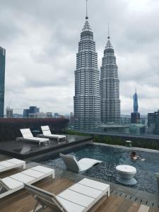 a swimming pool with chairs and a view of skyscrapers at Casaluma STAR KLCC in Kuala Lumpur