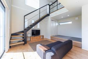 a living room with a staircase and a couch at 海まで徒歩7分庭とデッキでくつろぐ大人葉山の上質ステイ in Hayama
