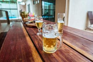 three glasses of beer sitting on a wooden table at Casa em Jacuma, com piscina, 5 suites e fliperama in Jacumã
