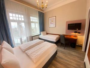 Una habitación de hotel con dos camas y un escritorio. en Hotel Kronprinz Hamburg Hauptbahnhof, en Hamburgo