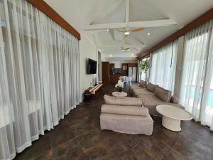 een woonkamer met een bank, stoelen en ramen bij Choeng Mon Bliss villa, pool private in Choeng Mon Beach