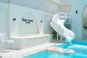 ein Schwimmbecken mit einer weißen Rutsche in einem Gebäude in der Unterkunft White Heaven Pool Villa Pattaya in Ban Nong Chaeng