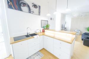 a kitchen with white cabinets and a sink at Très beau et grand T2, jardin et terrasse in Biarritz