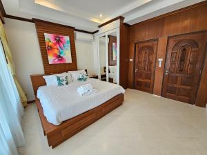 een slaapkamer met een groot bed met een houten hoofdeinde bij Choeng Mon Bliss villa, pool private in Choeng Mon Beach