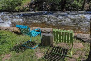 una sedia verde seduta accanto a un ceppo vicino a un fiume di Idlewilde by the River a Estes Park