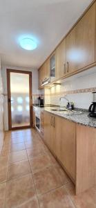 Una cocina con gabinetes de madera y piso de baldosas. en Albir Holidays Font Rotja, en Albir 1 foto más